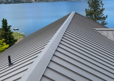 Nielsen Roofing installed new grey residential metal roof near lake